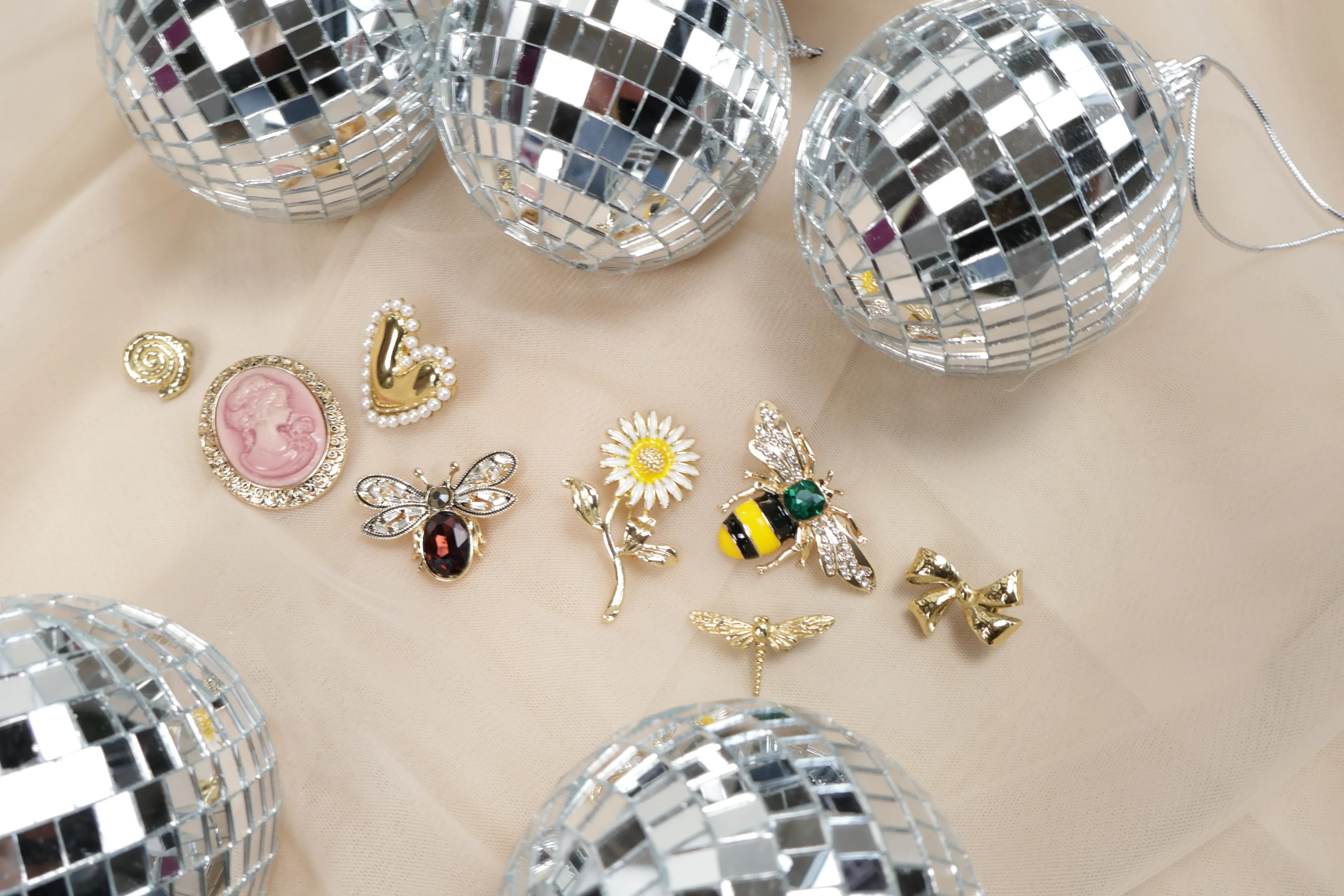Diverse_broches_op_beige_achtergrond_met_discoballen - Just the Jacket