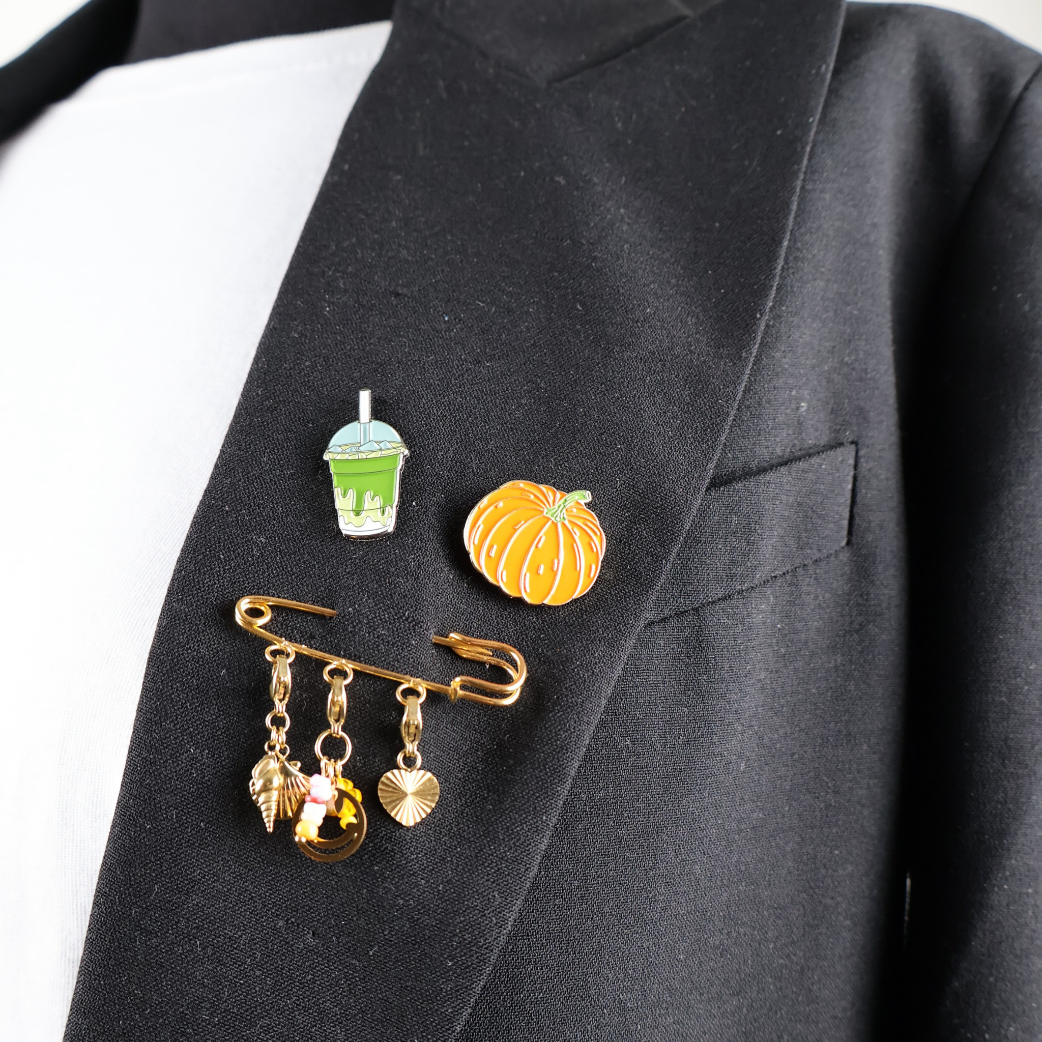 Épingle de sûreté dorée ornée de breloques colorées en forme de smiley, d'étoile de mer, de coquillage et de cœur