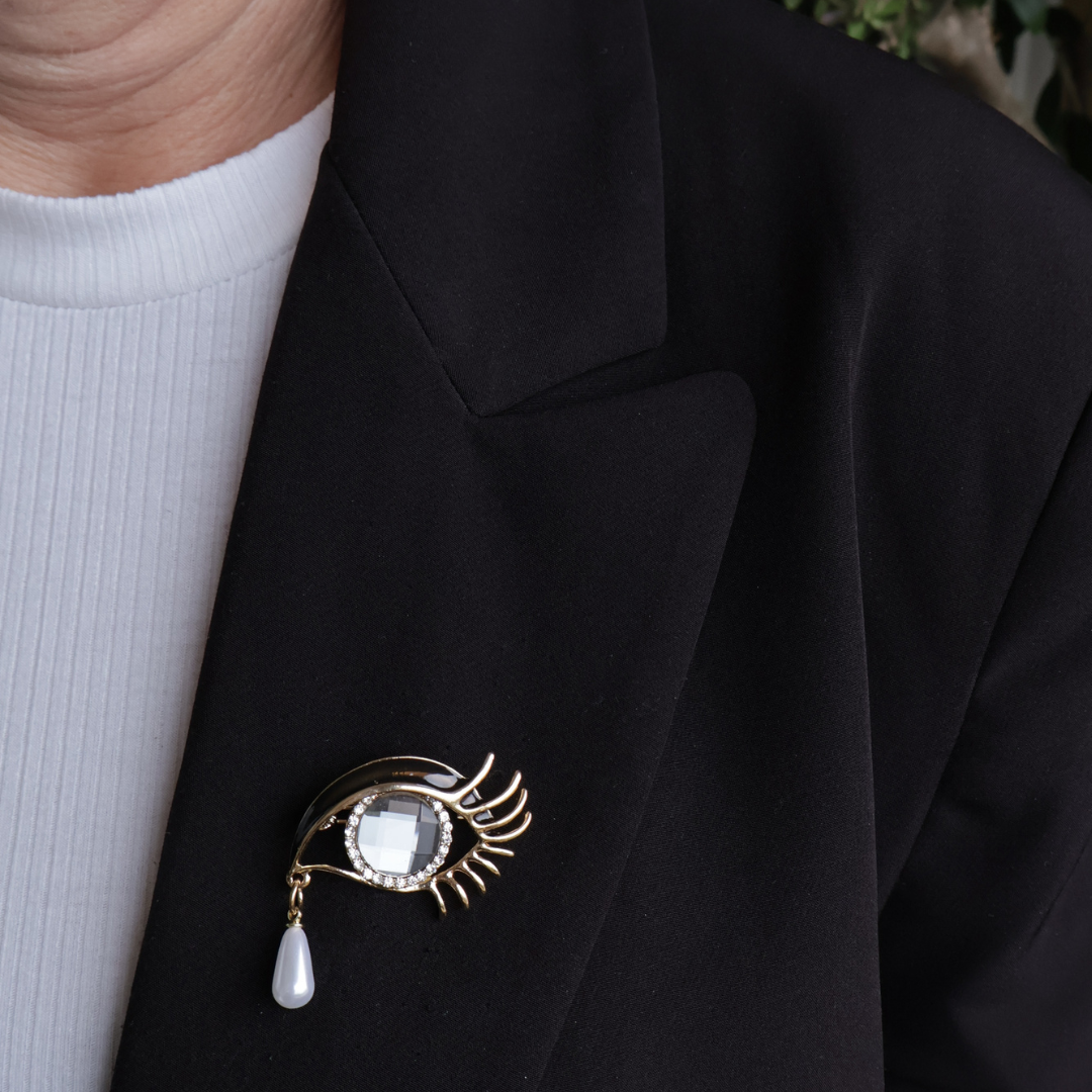 broche  oog met traantje op zwarte blazer