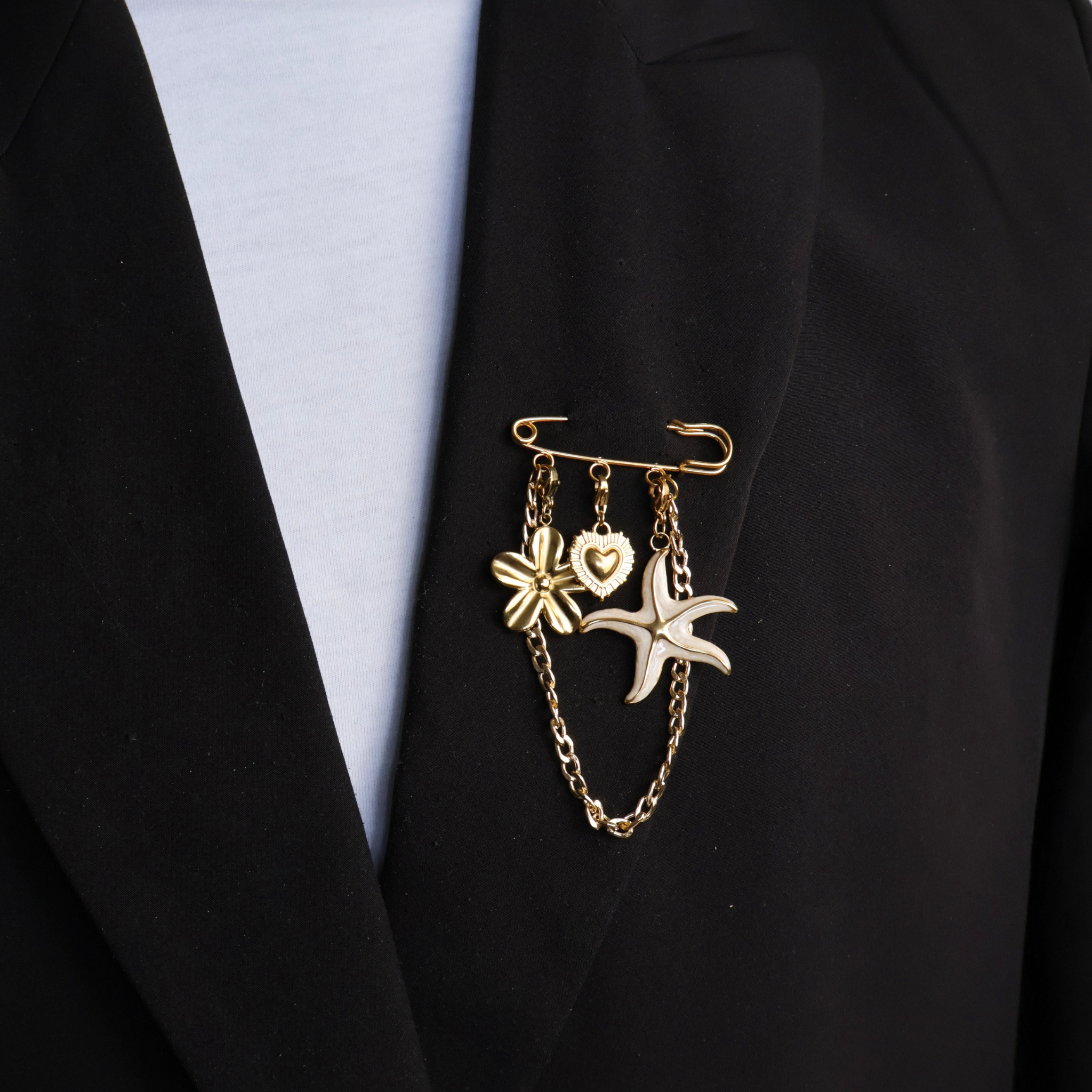 Gouden veiligheidsspeld met bloem, hart, zeester en gouden ketting