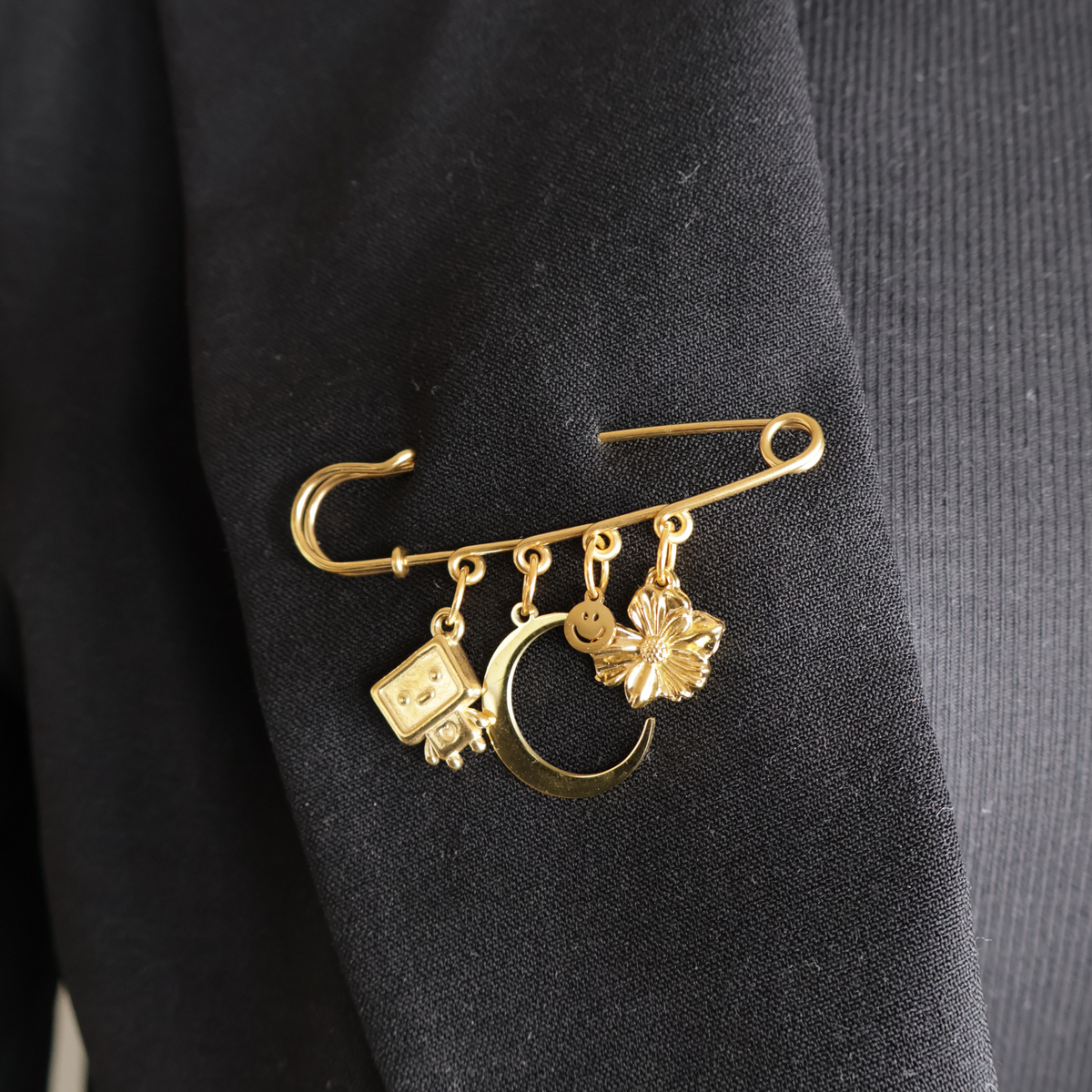 safety pin goud met bedels op zwarte blazer