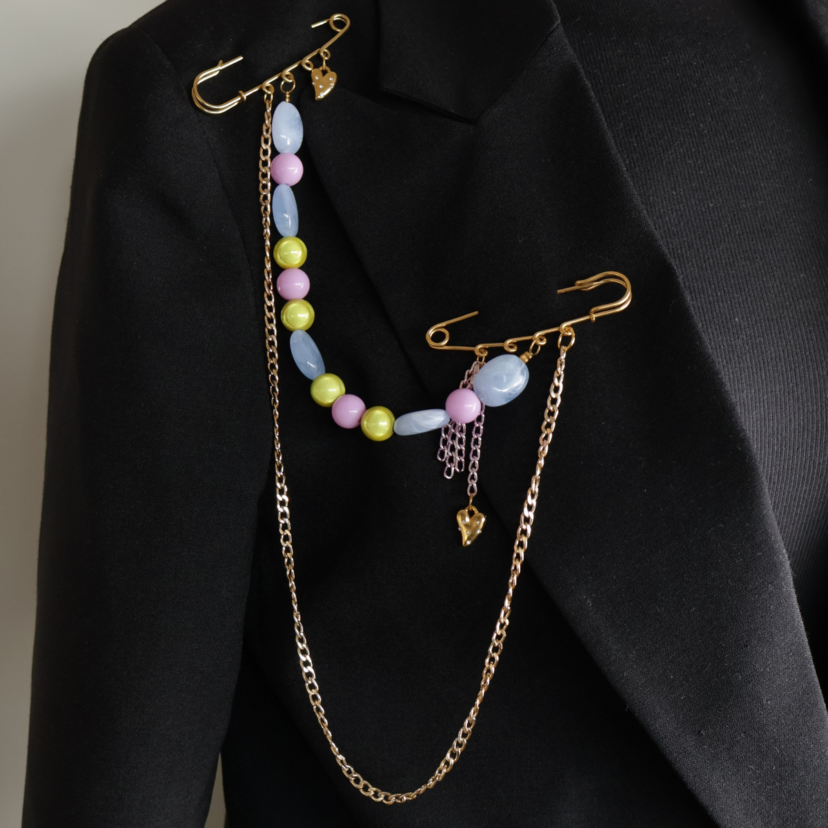 safety pin goud met gekleurde kralen blauw paars groen op zwarte blazer