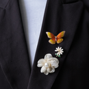 Zwarte blazer met oranje vlinder broche, wit mini bloem broche en beige tule met witte parel broche