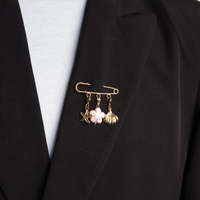 sierspeld goud met zeester schelp en roze bloem op zwarte blazer